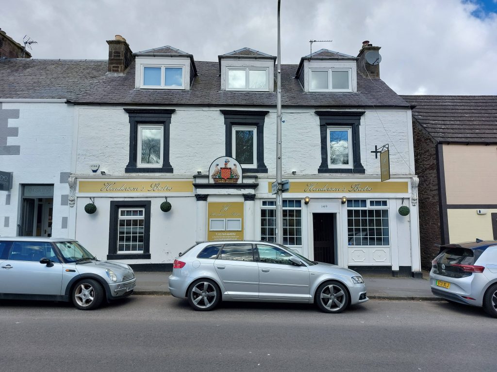The restaurant and pub opportunity is a three storey terraced building, with yellow signage and family crest above the main entrance